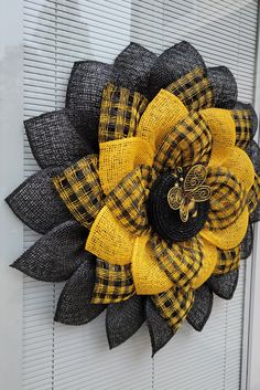 a yellow and black wreath with a bee on it's center piece is hanging on the front door