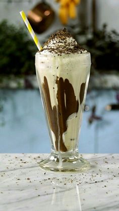 a milkshake with chocolate and whipped cream in a tall glass on a table