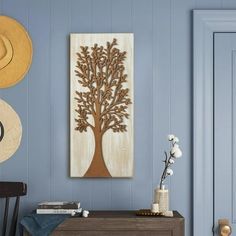 a wooden tree is hanging on the wall next to a blue door and hat rack