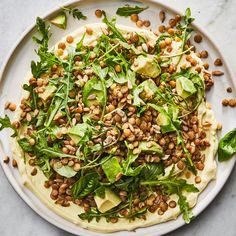 a white plate topped with spinach and avocado on top of a table