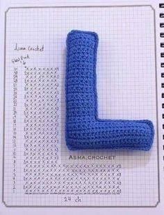 a crocheted blue object sitting on top of a notebook with the letter l in it