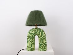 a green lamp sitting on top of a white table