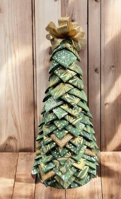 a christmas tree made out of green wrapping paper on top of a wooden table next to a fence