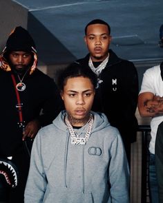 three young men standing next to each other in front of a wall with shark teeth on it