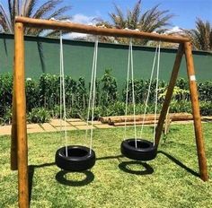 two tire swings in the grass with palm trees behind them