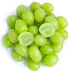 green grapes in a white bowl on a white surface