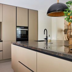 a kitchen with marble counter tops and beige cabinets