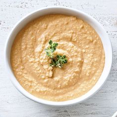 a white bowl filled with hummus and garnished with parsley