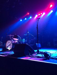 the band is performing on stage with bright lights coming from their drums and microphones