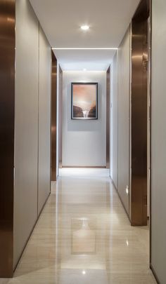 an empty hallway leading to two elevators and a painting hanging on the wall above it