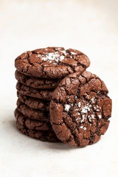 a stack of chocolate cookies with powdered sugar on top and one cookie in the middle