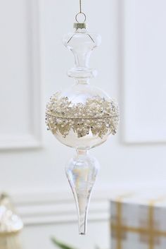 a clear glass ornament hanging from a gold and white christmas tree with ornaments around it