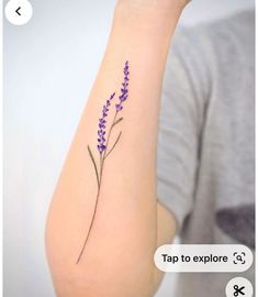 a purple flower is on the arm of a woman's right arm, which has an arrow tattoo that reads tap to explore