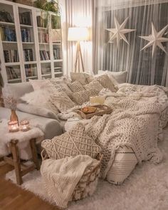 a living room filled with lots of pillows and blankets on top of a white rug