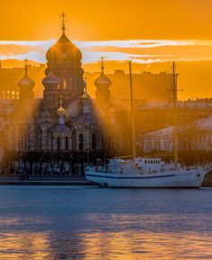 the sun is setting over an old building and some boats in the water near it