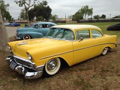 an old yellow car is parked in the grass