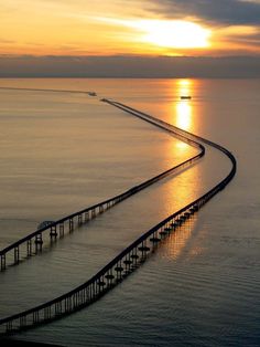 an aerial view of a long bridge in the middle of the ocean at sunset or sunrise