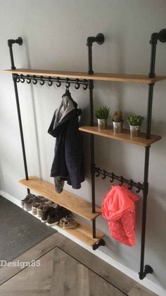 a coat rack with shoes and coats hanging on the wall next to a potted plant