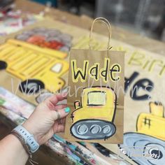 a person holding up a brown paper bag with the words wade on it and a yellow school bus drawn on it