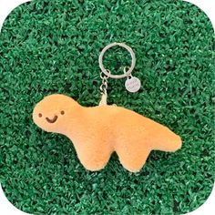 a stuffed animal keychain with a smiley face on it's side laying in the grass