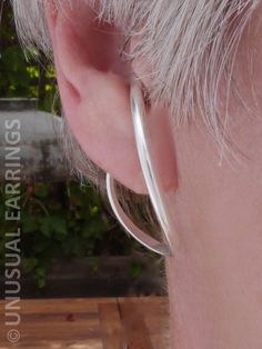 an older man's ear is shown with a thin silver hoop in the middle