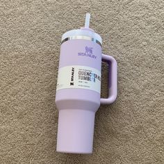 a purple tumbler cup sitting on top of a carpeted floor next to a wall