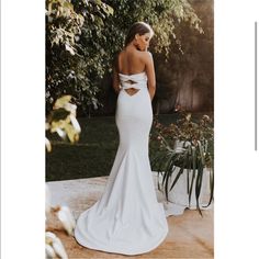 a woman in a white wedding dress standing on a patio with her back to the camera