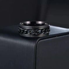 a black wedding ring sitting on top of a piece of luggage in front of a black background