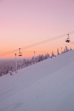 a person riding skis down a snow covered slope at sunset with the lift in the background