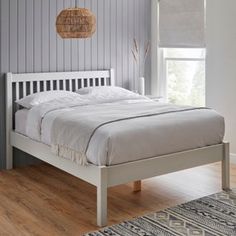 a bed sitting on top of a hard wood floor next to a window with blinds