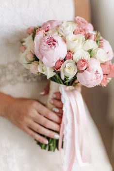 a bride holding a bouquet of pink and white flowers