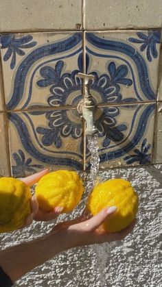 someone is holding two lemons under a faucet