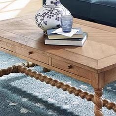 a coffee table with some books on it and a vase sitting on top of it