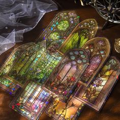 several stained glass windows sitting on top of a wooden table next to a white veil