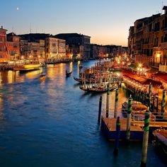 the city is lit up at night and there are many boats in the water