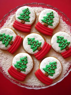 decorated cookies in the shape of christmas trees on a platter with powdered sugar