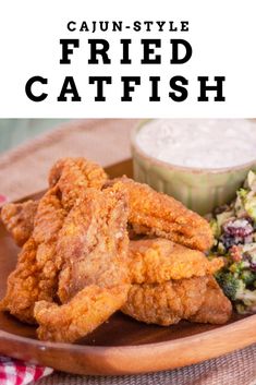 fried fish served with salad and dressing on a wooden platter that says, cajun - style fried catfish