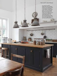 a kitchen with an island and wooden table in the center, surrounded by hanging lights