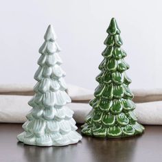 two ceramic christmas trees sitting on top of a table