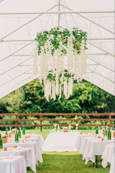 an outdoor tent with tables, chairs and chandelier hanging from it's ceiling