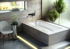 a bathroom with a large bathtub next to a chair and potted plant in the corner