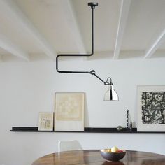 a wooden table topped with a bowl of fruit next to a shelf filled with pictures