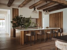 a kitchen with an island and bar stools in the center, surrounded by wood paneling