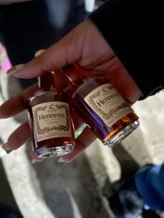 two bottles of hennesy are being held by someone's hand