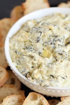 a white bowl filled with dip surrounded by crackers