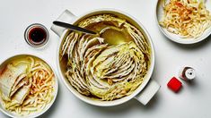 two white bowls filled with food next to another bowl full of noodles and sauces