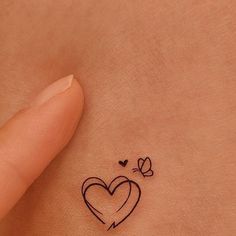 a small heart tattoo on the back of a woman's left side ribcage