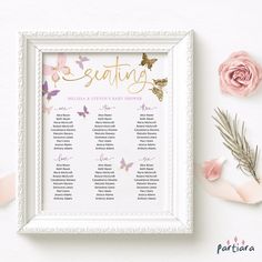 a seating chart with pink flowers and butterflies on the wall next to it is a white frame