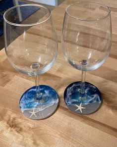 two wine glasses sitting next to each other on a wooden counter top with blue and white designs