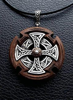 a wooden cross pendant on a black leather surface